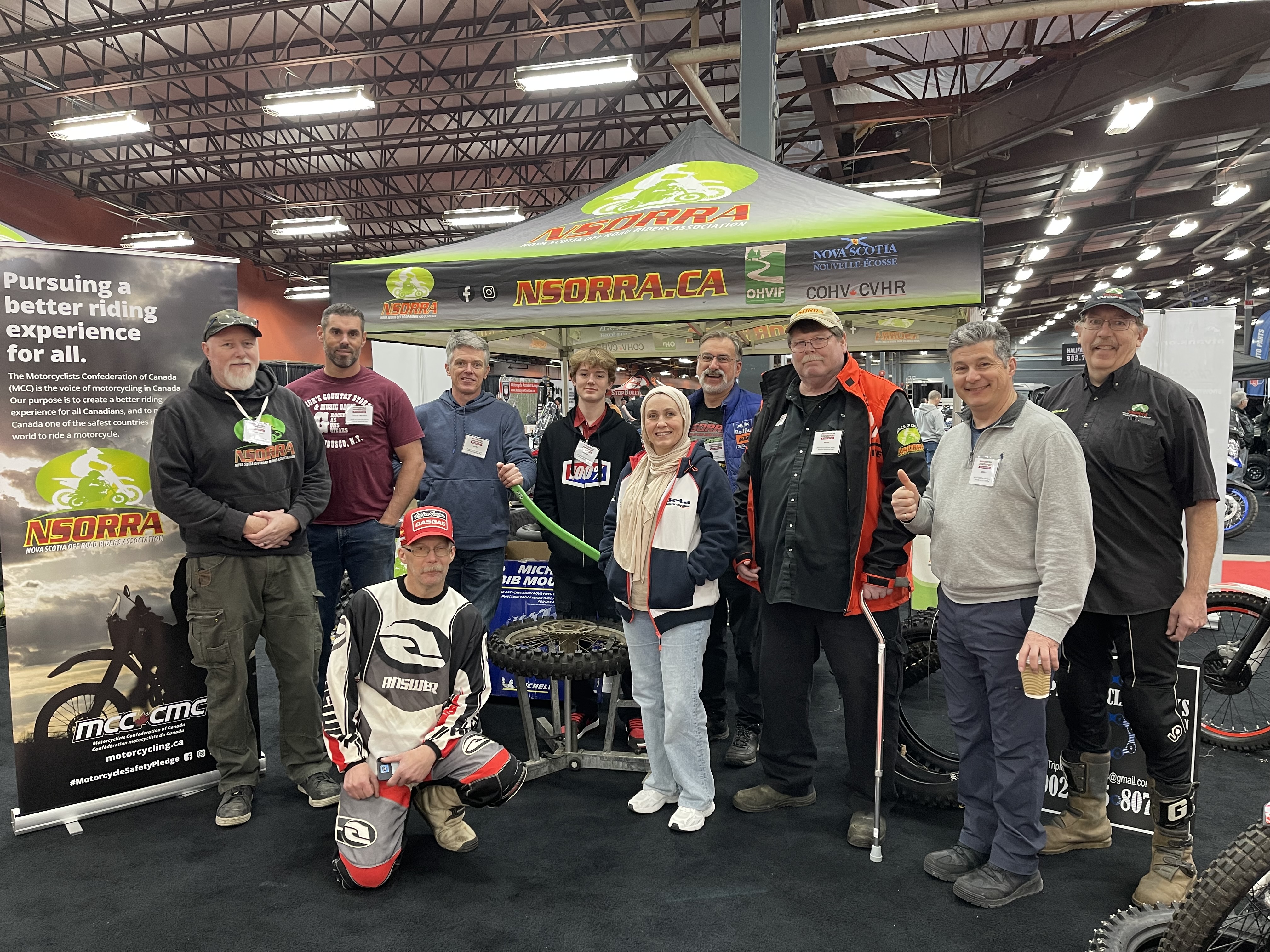 Several NSORRA booth volunteers pose in front of the NSORRA display at the Moto Show